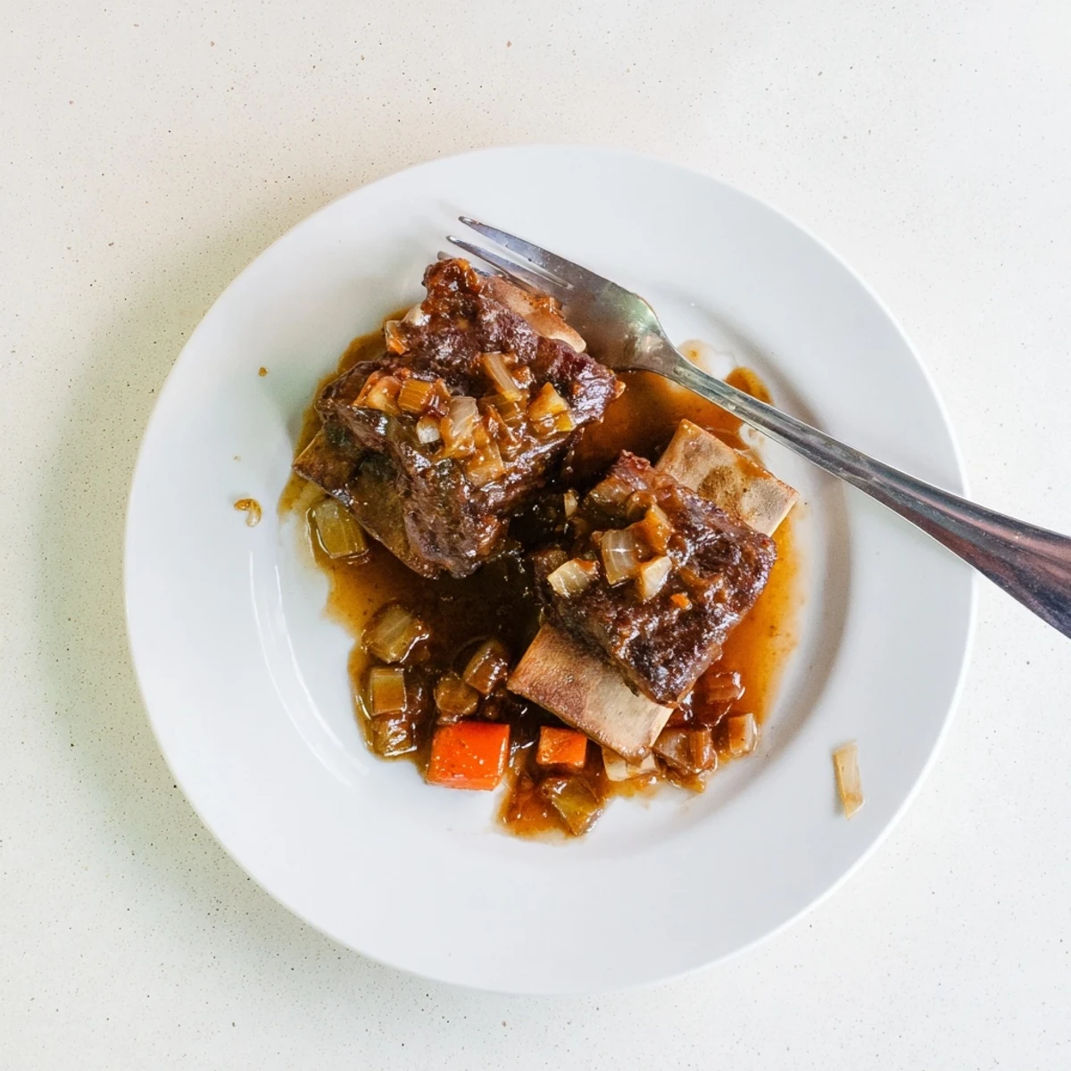 Braised short ribs drizzled with thick amber maple bourbon sauce alongside fresh herb garnish