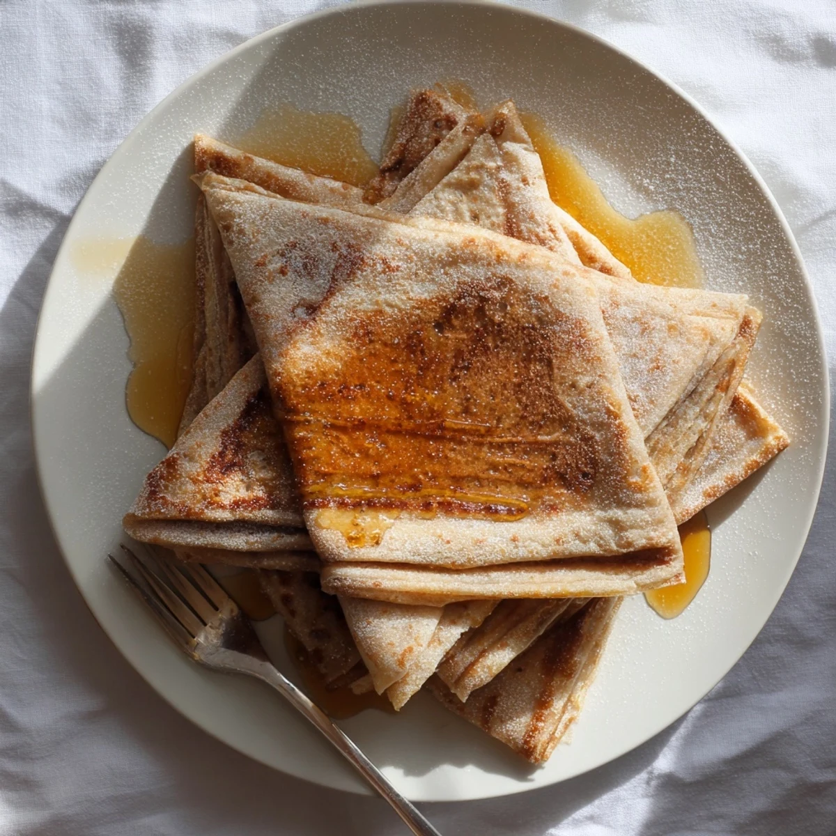 Flaky Meloui layered pancakes being cooked in a skillet until golden brown and crispy