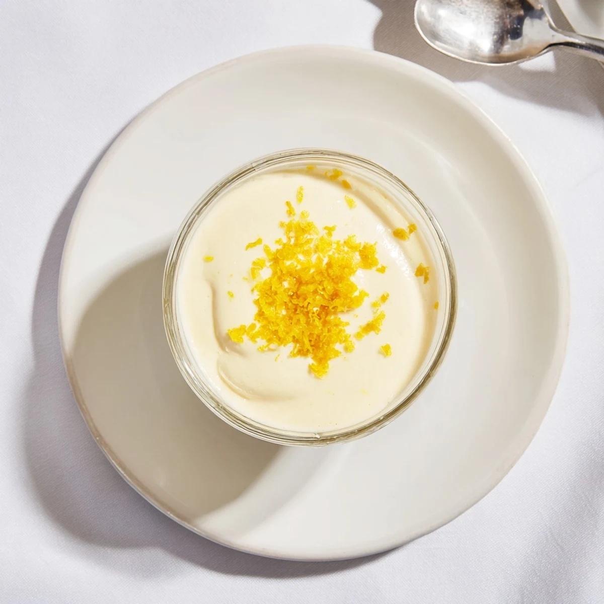 Golden lemon posset pudding chilled in small glass dish with shortbread cookie on the side