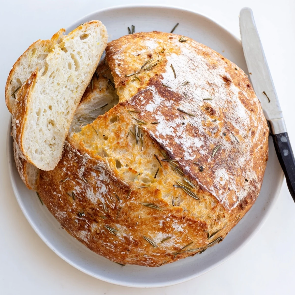 Golden crust Dutch oven garlic rosemary bread with fresh herbs and steam rising