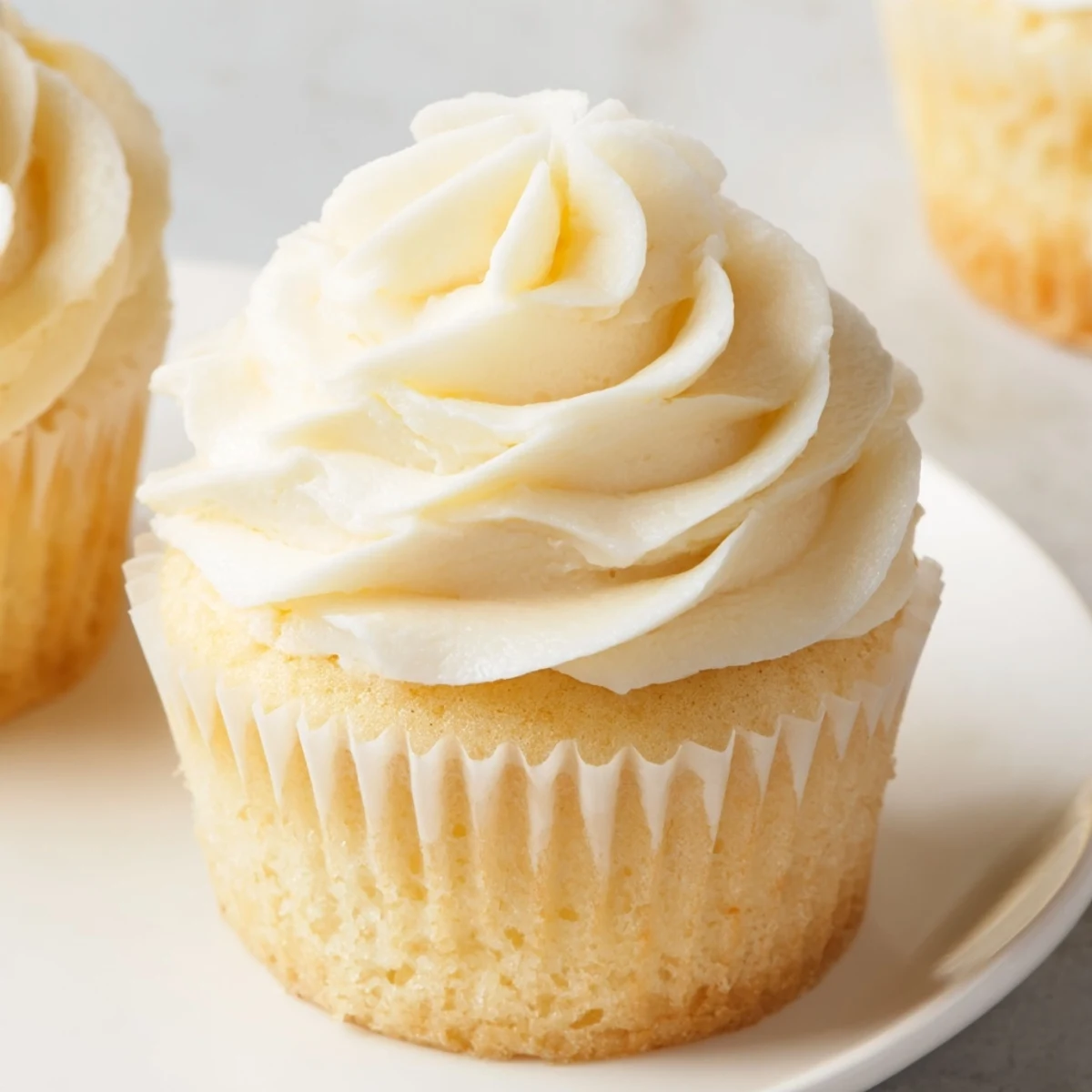 Golden homemade vanilla cupcakes with tall swirls of vanilla bean buttercream frosting