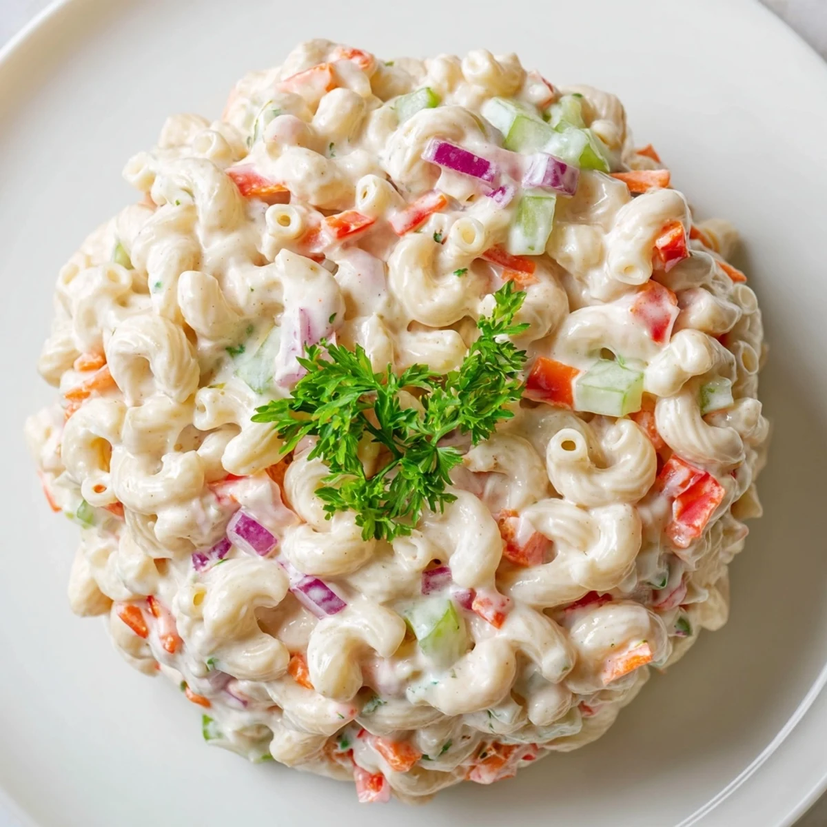 Creamy macaroni salad with colorful diced vegetables and tangy dressing in white serving bowl