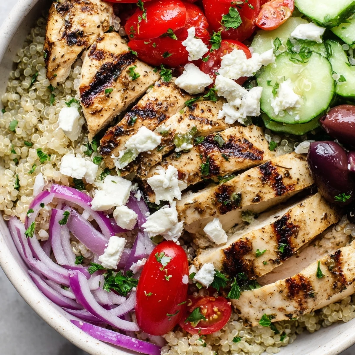 Golden grilled chicken tops a colorful Mediterranean chicken quinoa bowl with fresh vegetables