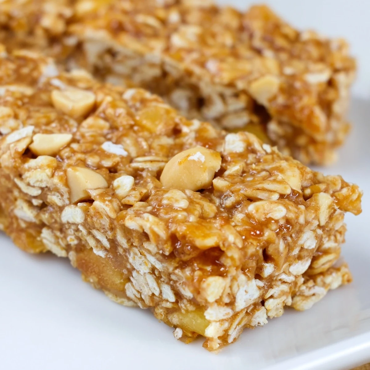 Thick no bake apple peanut butter granola bars sliced and stacked on a rustic wooden cutting board