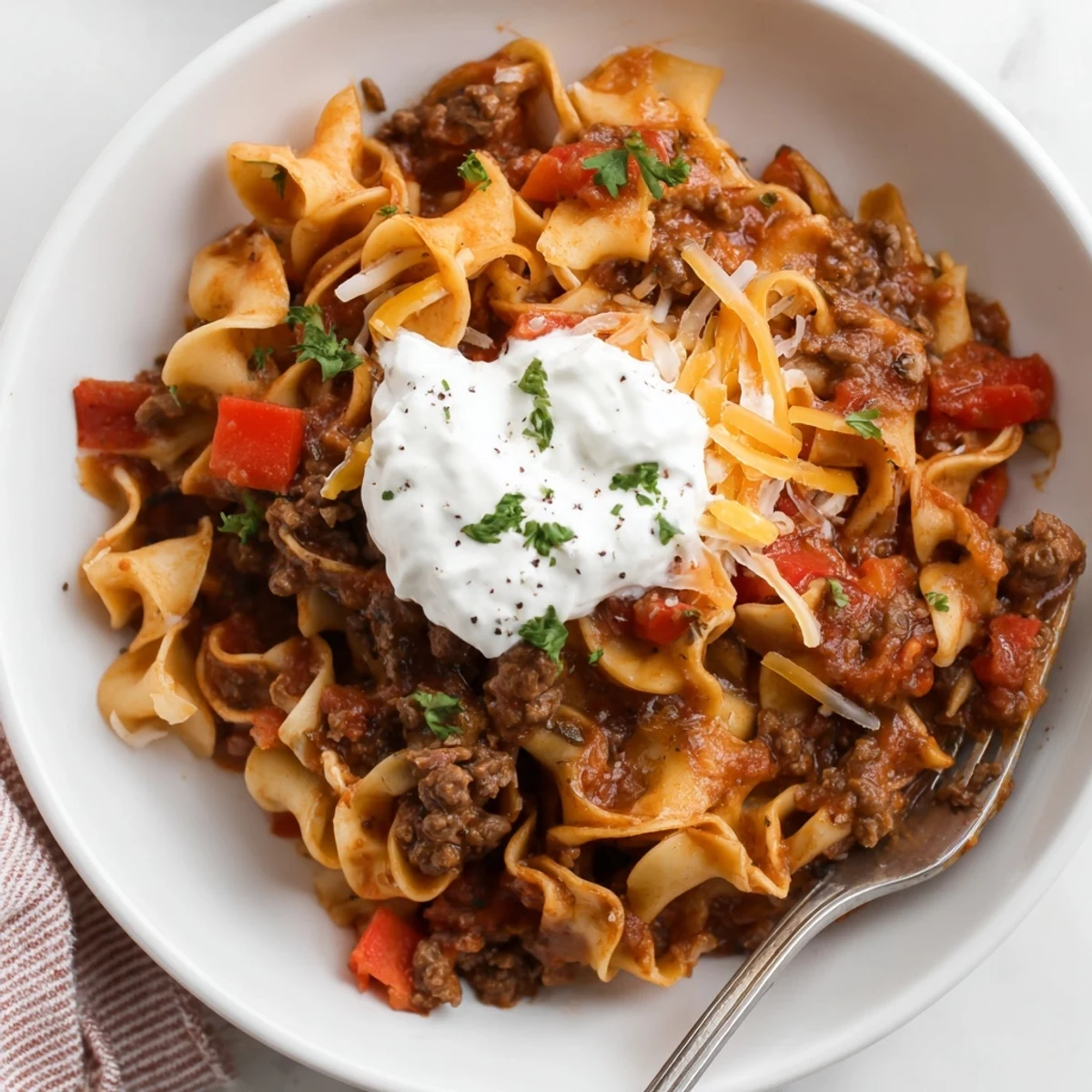 Creamy Beef Noodle Casserole topped with browned cheddar, paired with garlic bread