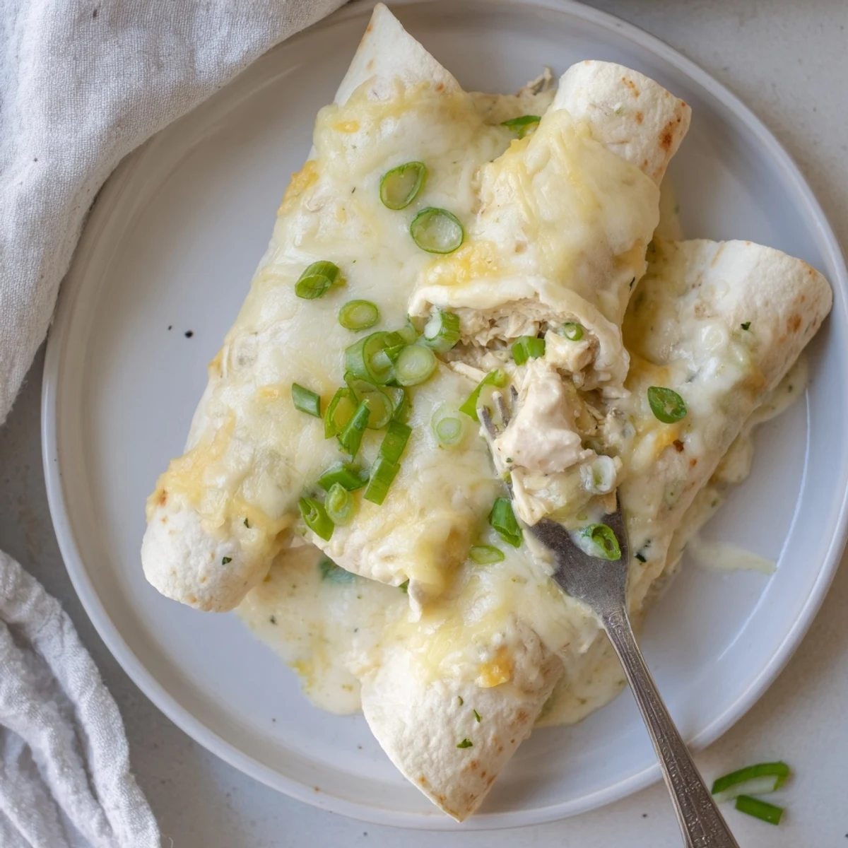 Creamy White Chicken Enchiladas baking in dish, bubbling golden cheese and sauce