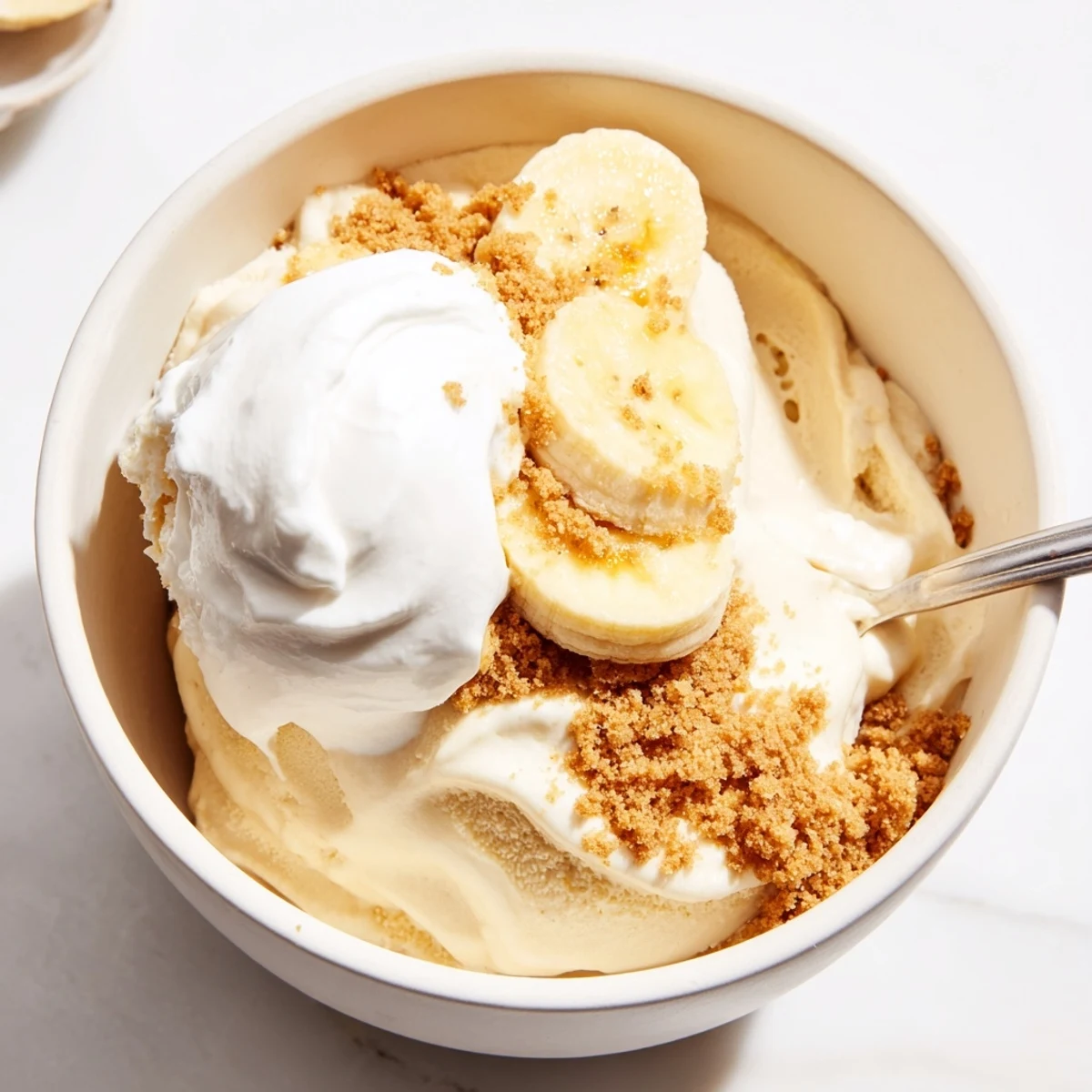Scoops of Ninja Creami Banana Cream Pie Ice Cream in bowls, sliced bananas