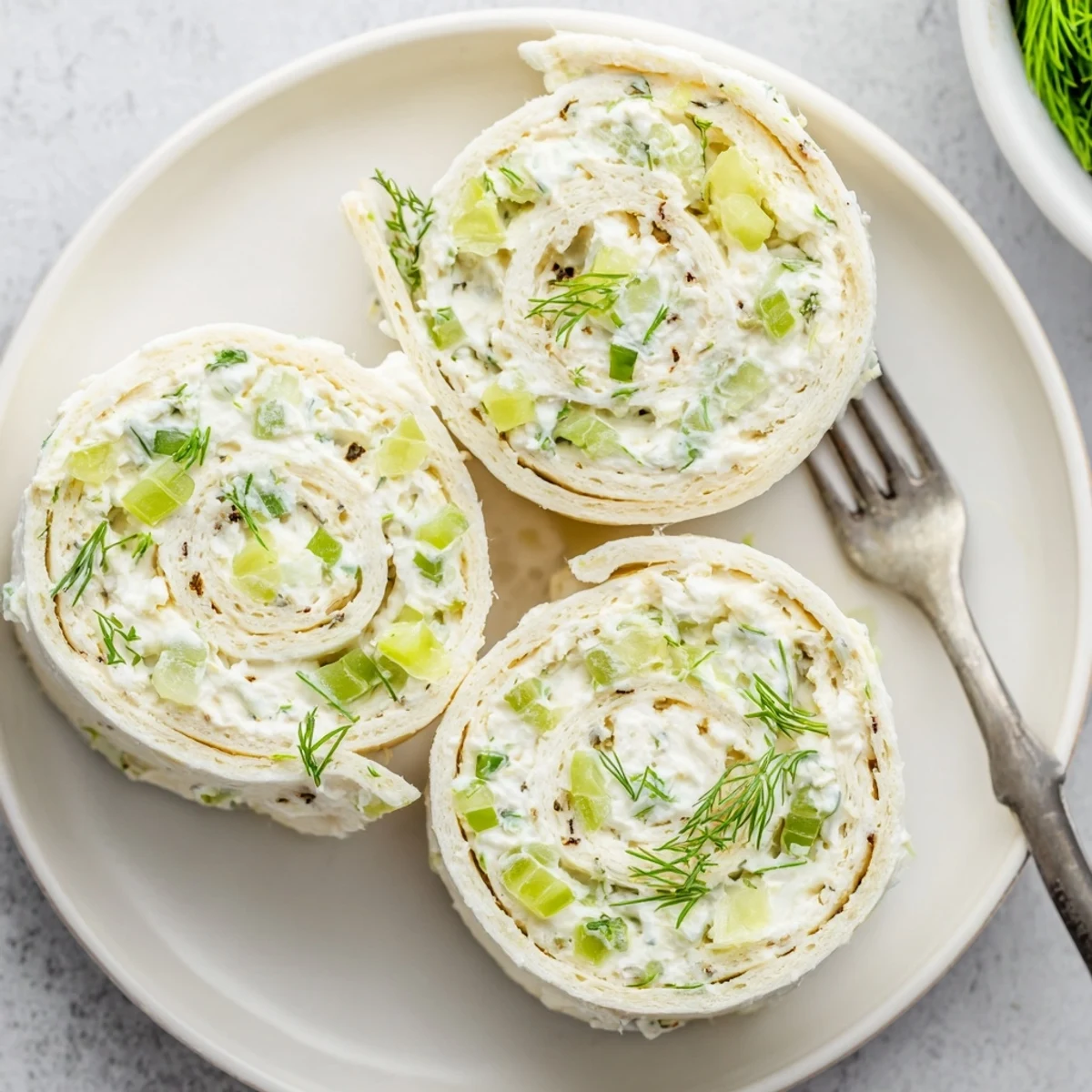 Party-ready Pickle Dip Pinwheels chilled after rolling, studded with chopped green onions