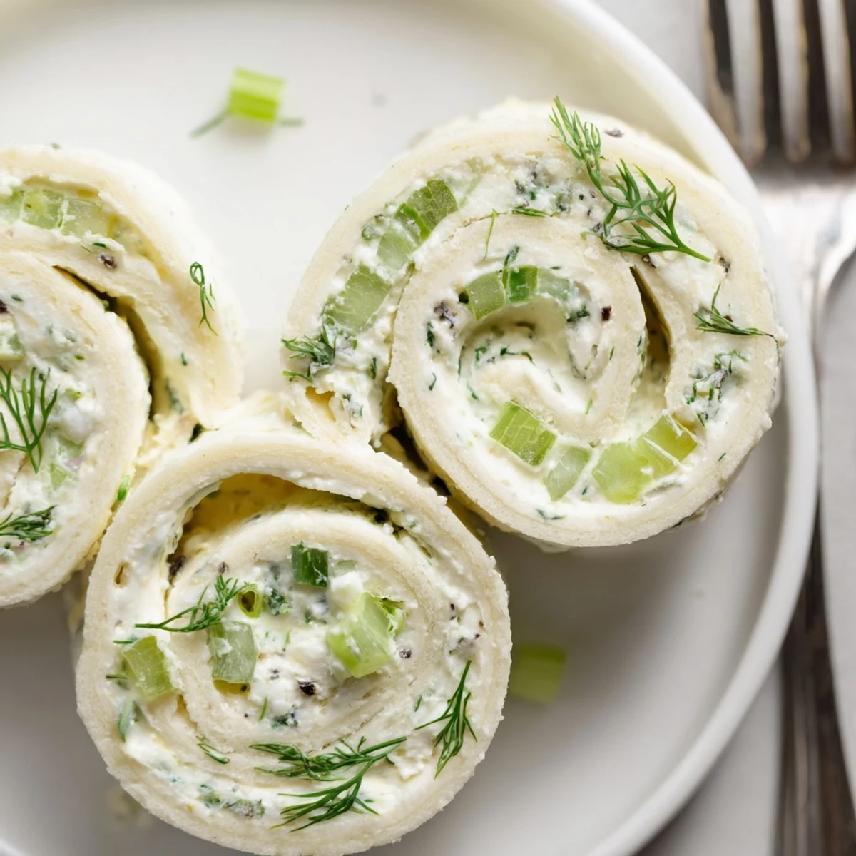 Soft tortilla Pickle Dip Pinwheels sliced into bite-sized rounds with fresh dill
