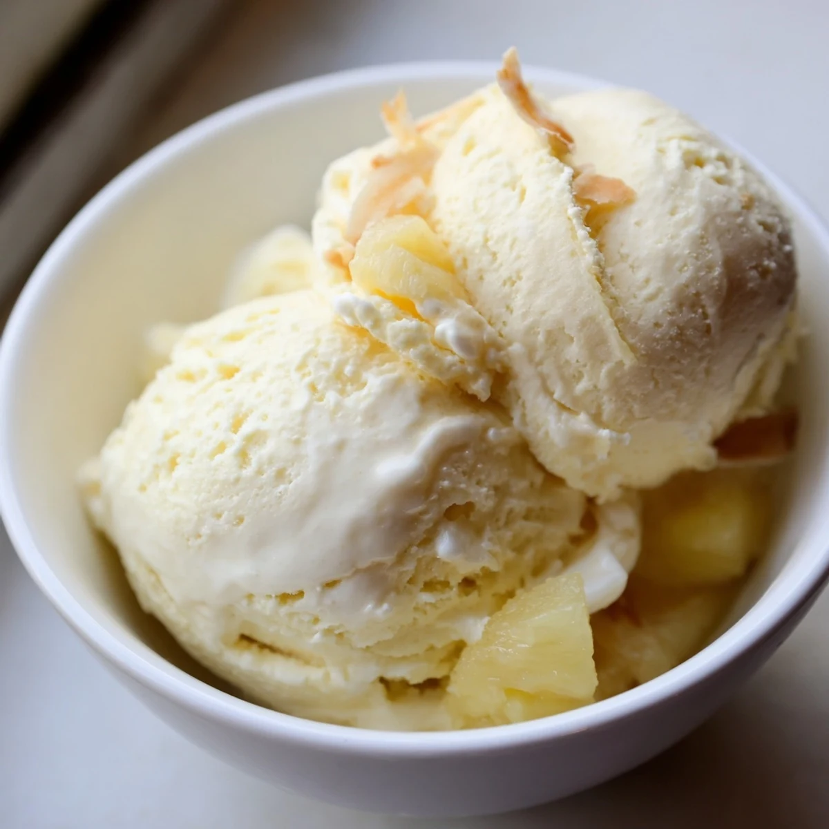 Creamy Pineapple Ice Cream scoops glistening with tropical aroma, served in bowl