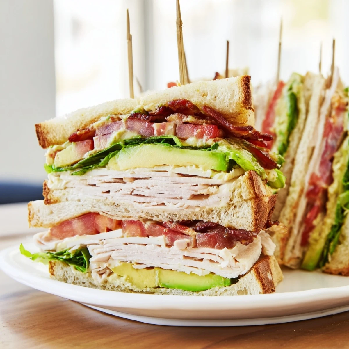Golden toasted California Club Sandwich stacked with turkey, bacon, avocado, and fresh tomato layers