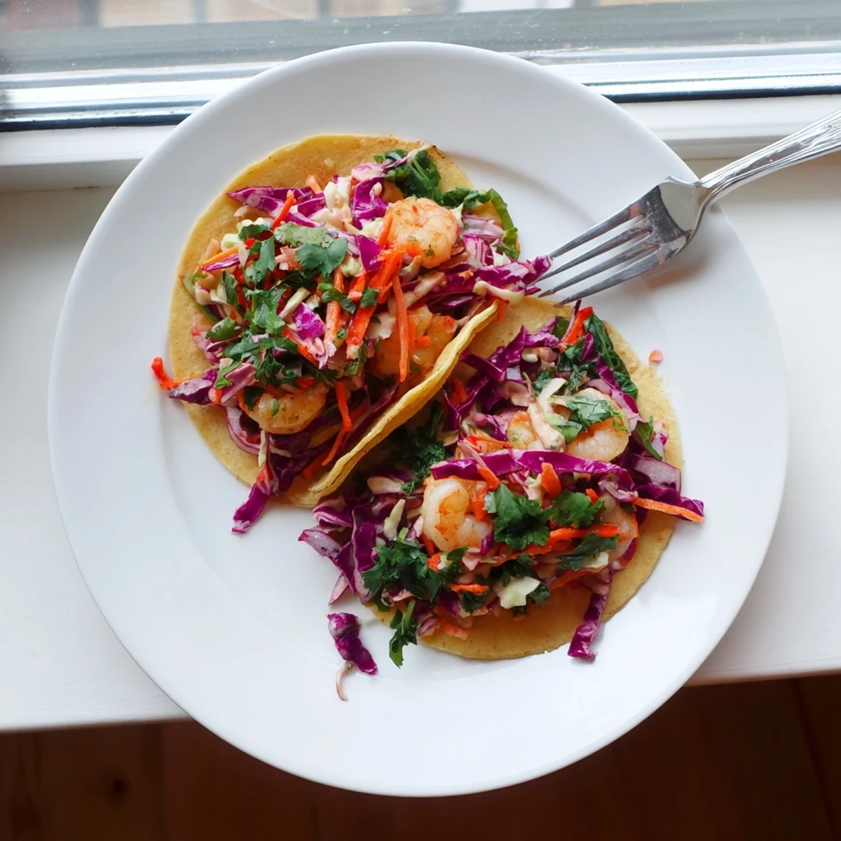 Spicy shrimp nestled in soft corn tortillas with crunchy tangy coleslaw and fresh cilantro garnish