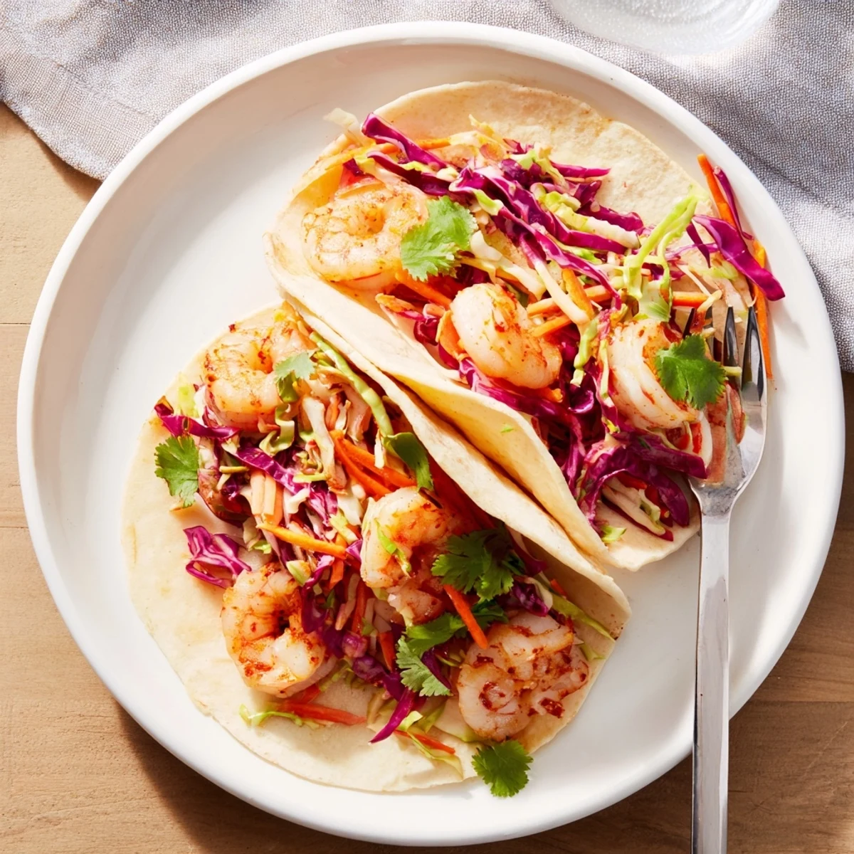 Platter of shrimp tacos with crisp red cabbage slaw and lime wedges for casual Mexican dinner
