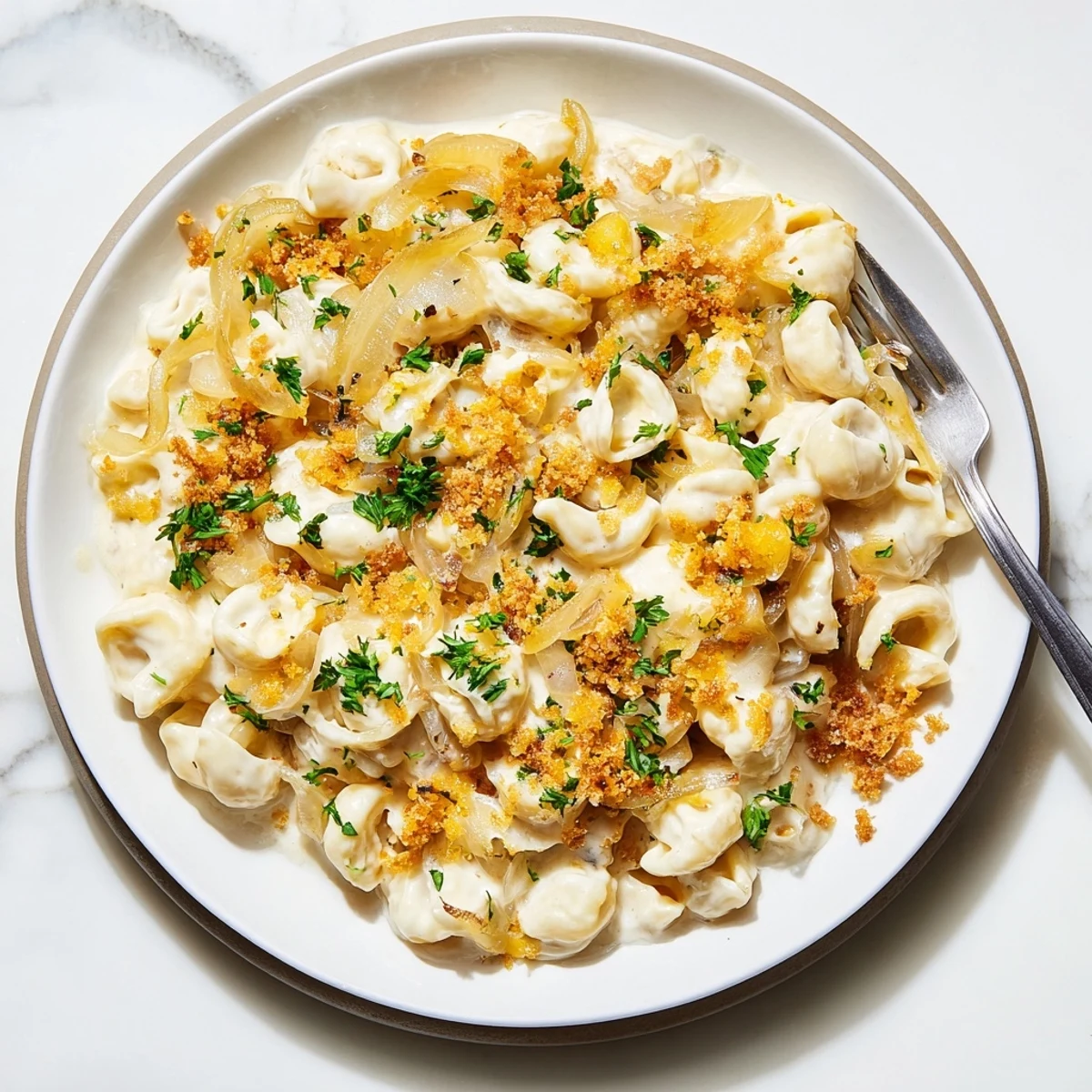 Bubbling French onion mac and cheese baked in a white dish with rich Gruyère cheese sauce