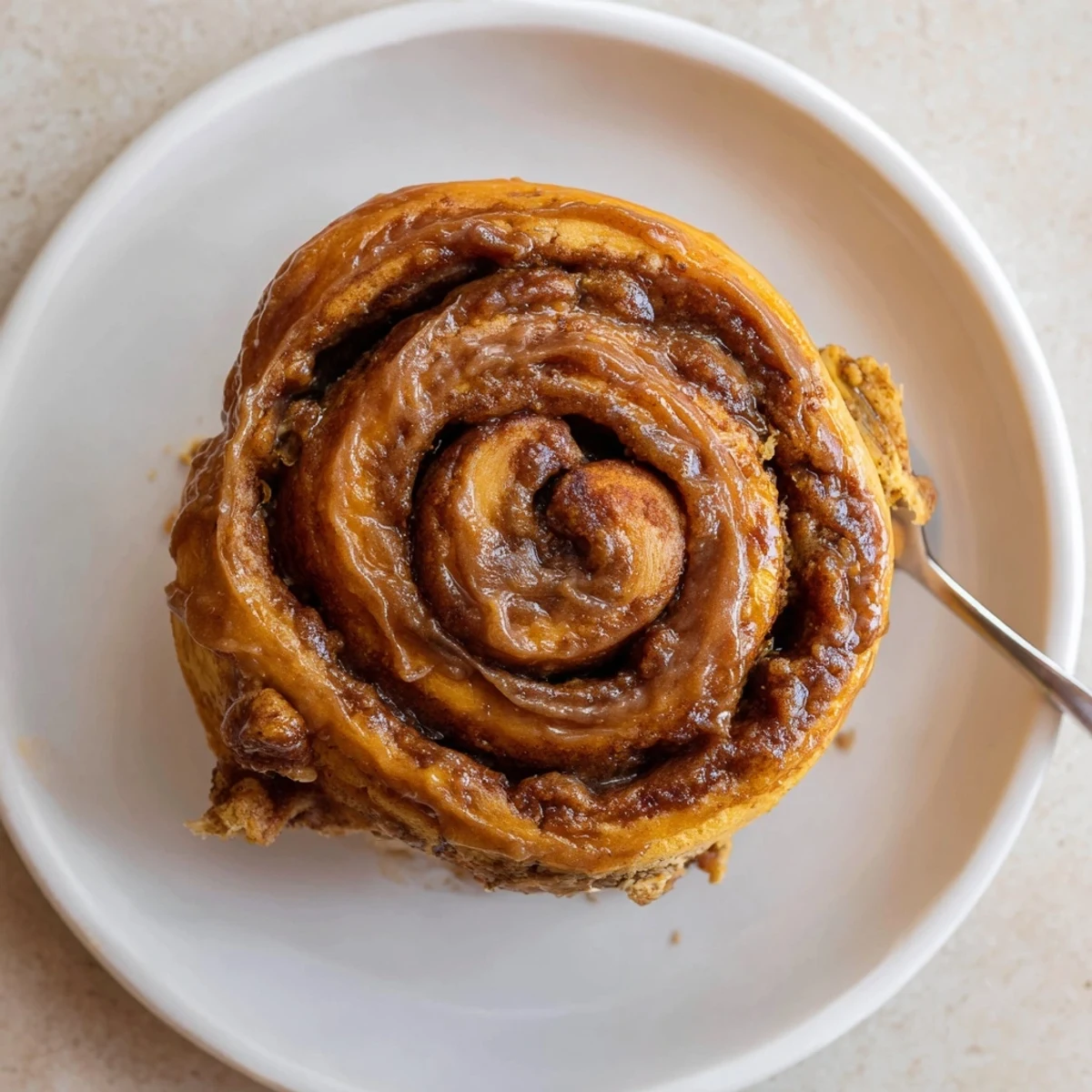 Warm Banana Bread Cinnamon Rolls topped with cream cheese icing, steaming.
