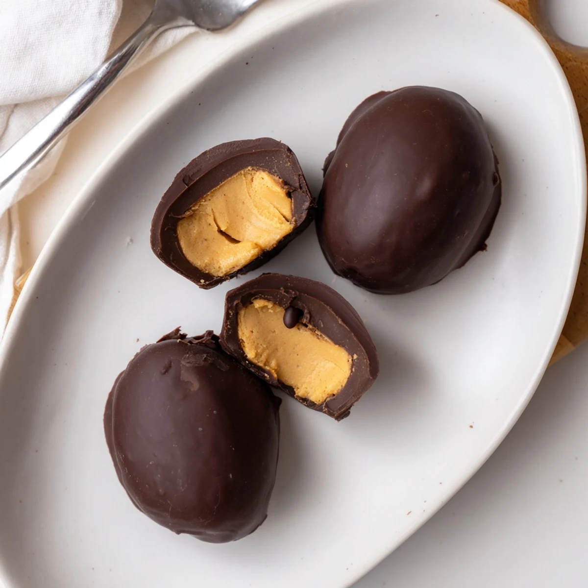 Homemade Peanut Butter Eggs with glossy chocolate coating, creamy centers chilled on parchment