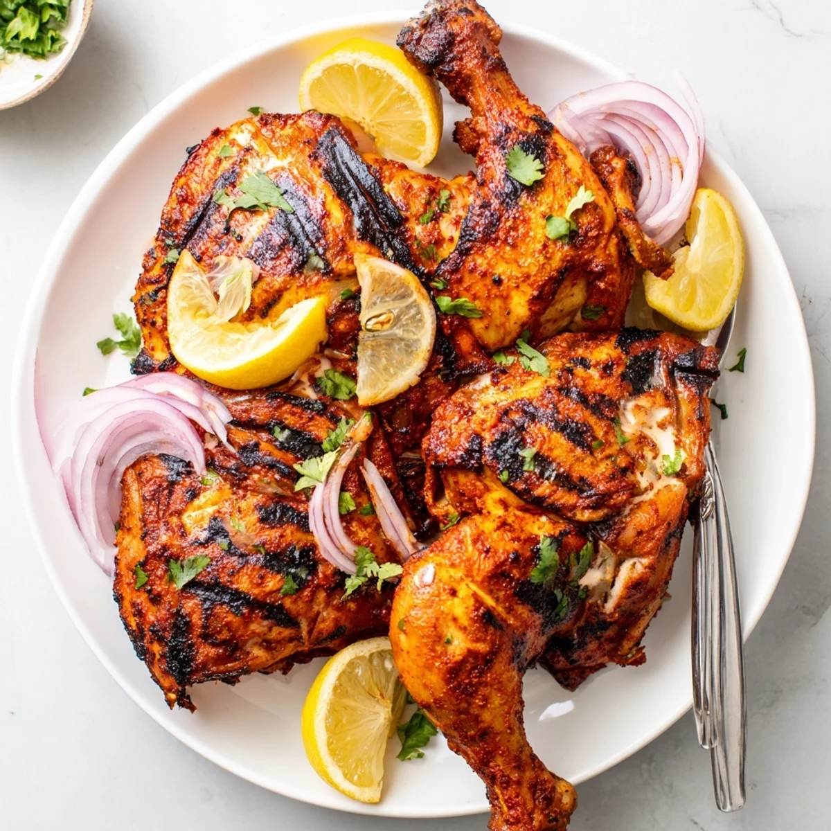 Smoky Grilled Spicy Tandoori Chicken resting on plate with lemon wedges
