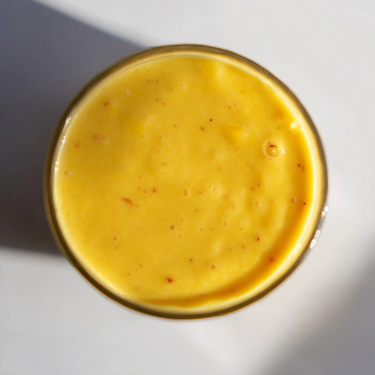 Golden tropical pineapple mango smoothie recipe poured into glasses with fresh fruit garnish and lime