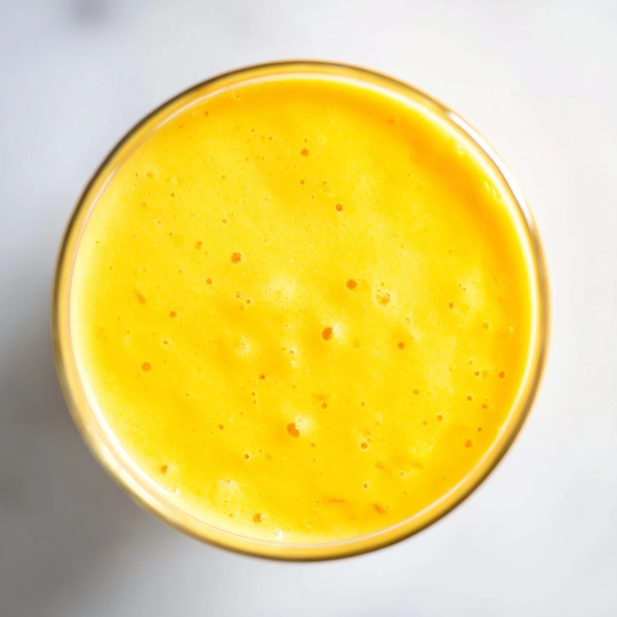 Thick refreshing pineapple mango smoothie recipe in tall glasses topped with mint and pineapple wedges