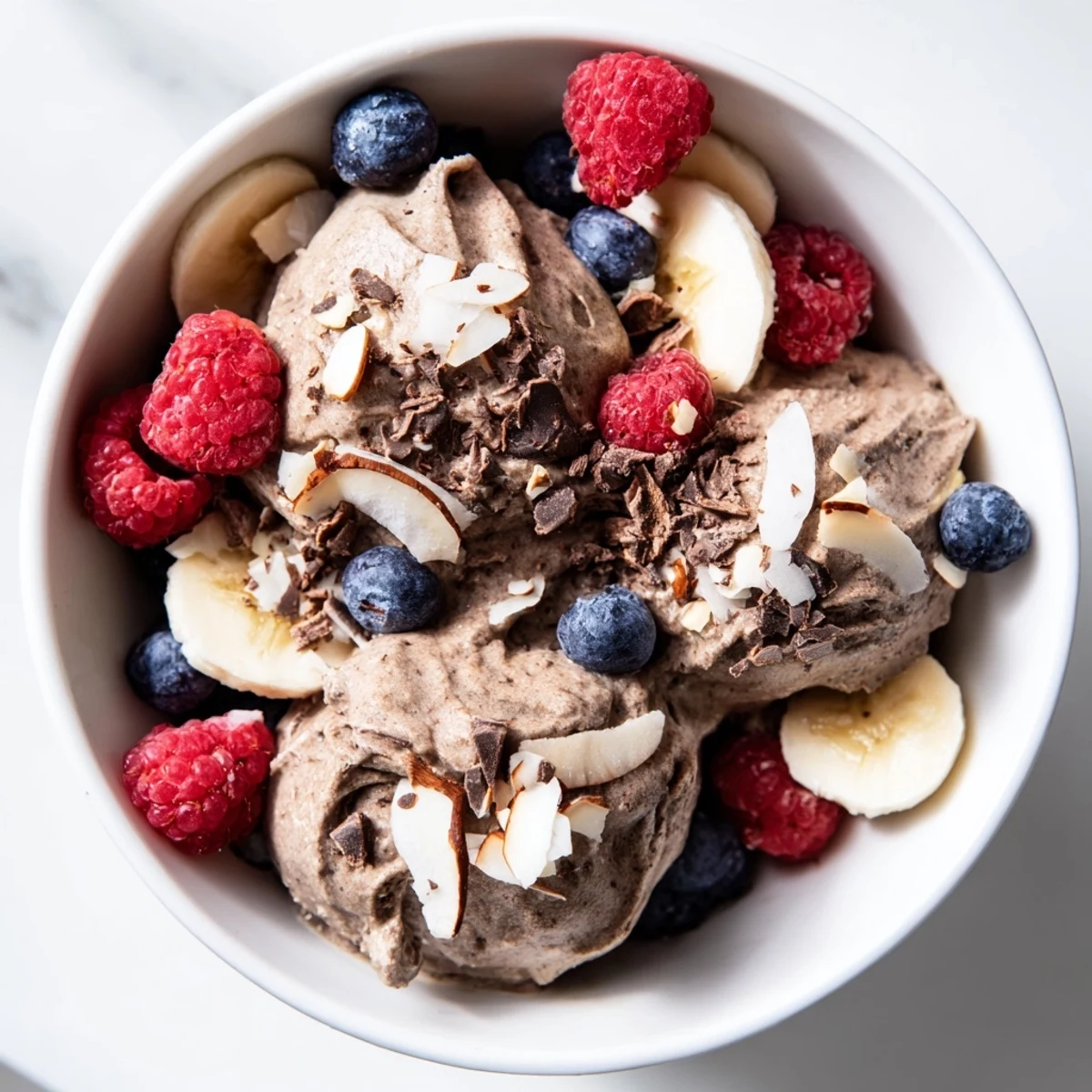 Vibrant banana-based healthy nice cream swirled with frozen berries and topped with coconut flakes