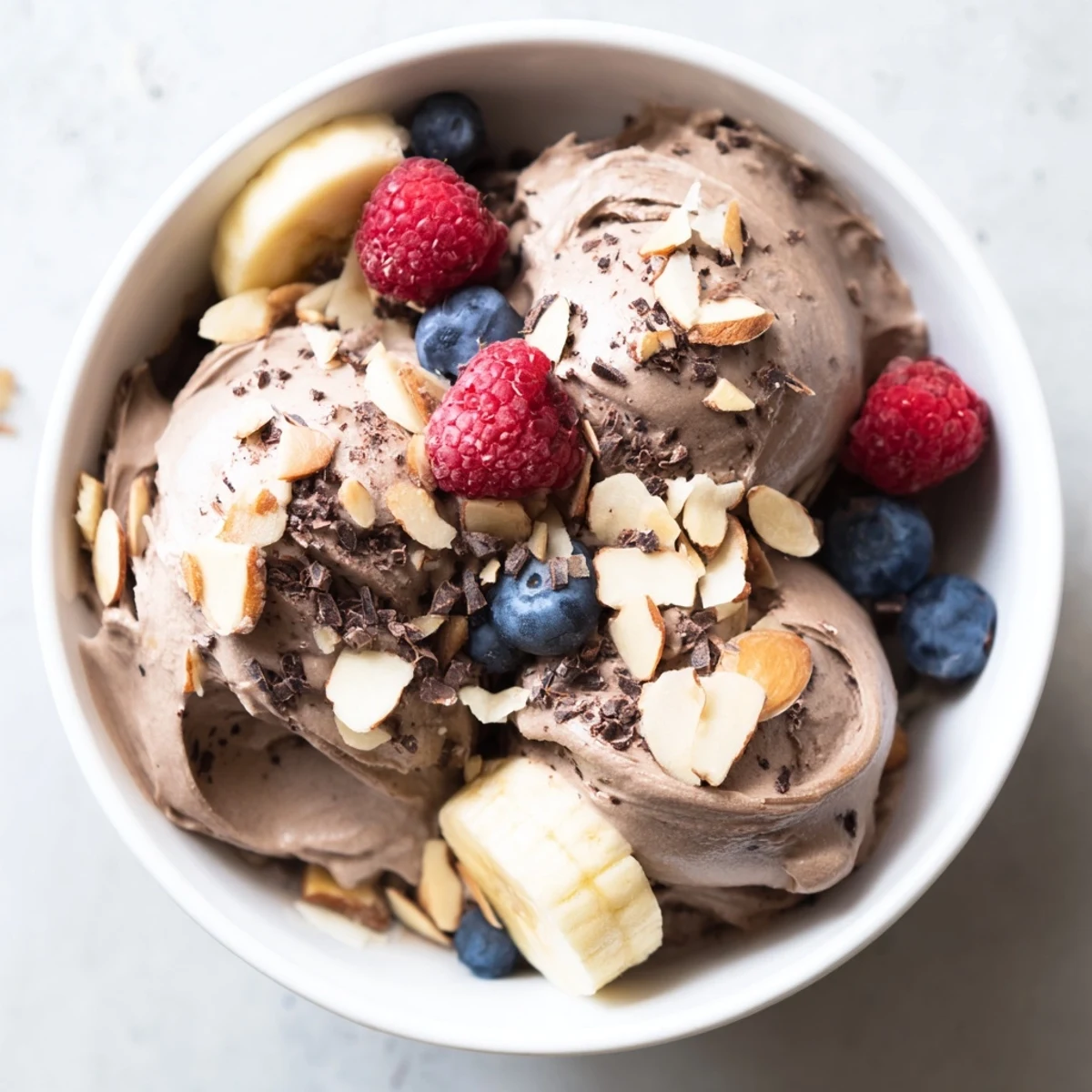 Smooth dairy-free healthy nice cream scooped into glasses with chopped nuts and fresh banana slices