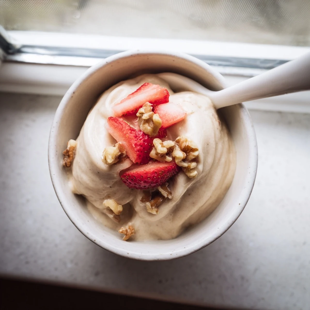 Creamy healthy nice cream served in bowls topped with fresh berries and crunchy nuts