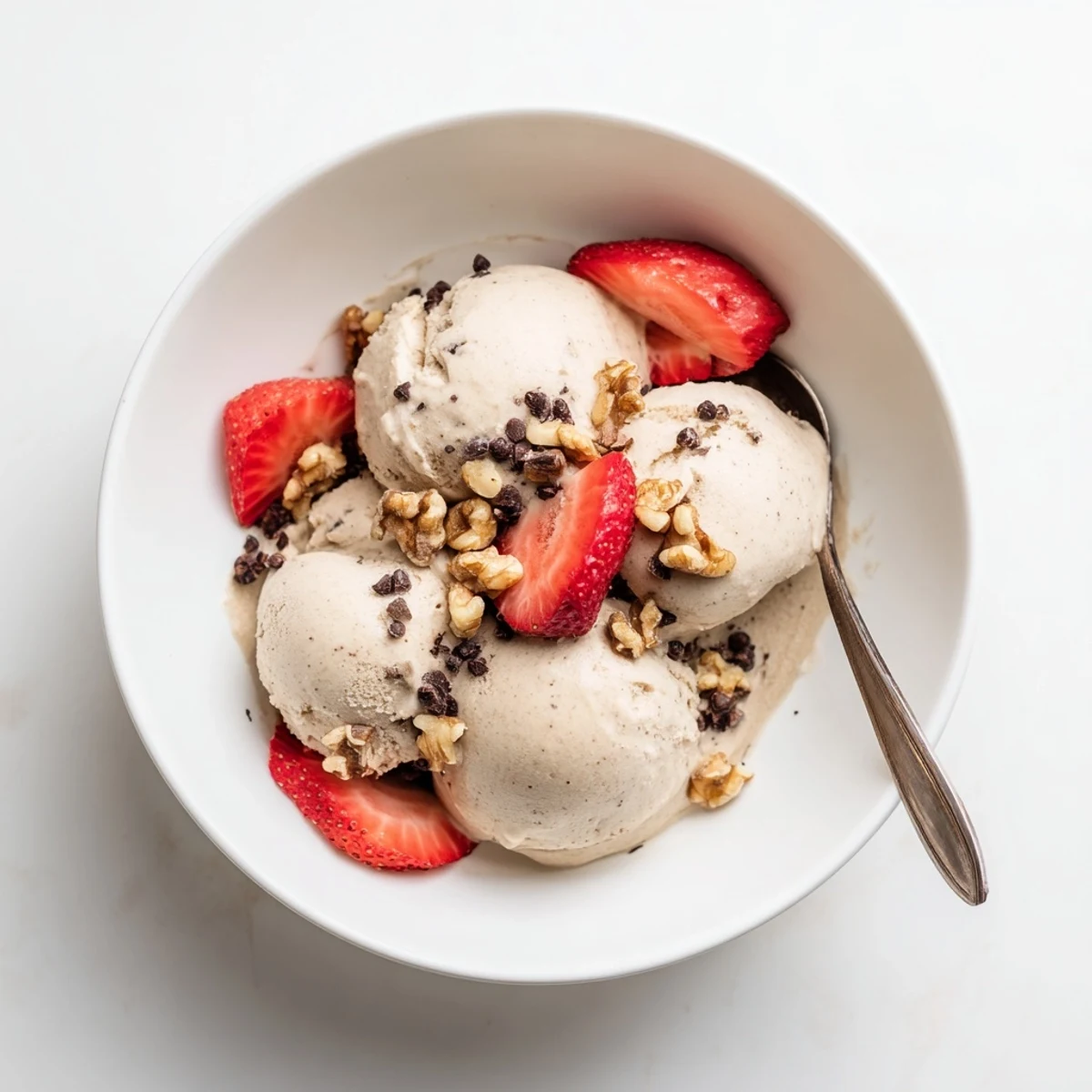 Vegan banana nice cream swirled in a white bowl with chocolate chips and coconut flakes