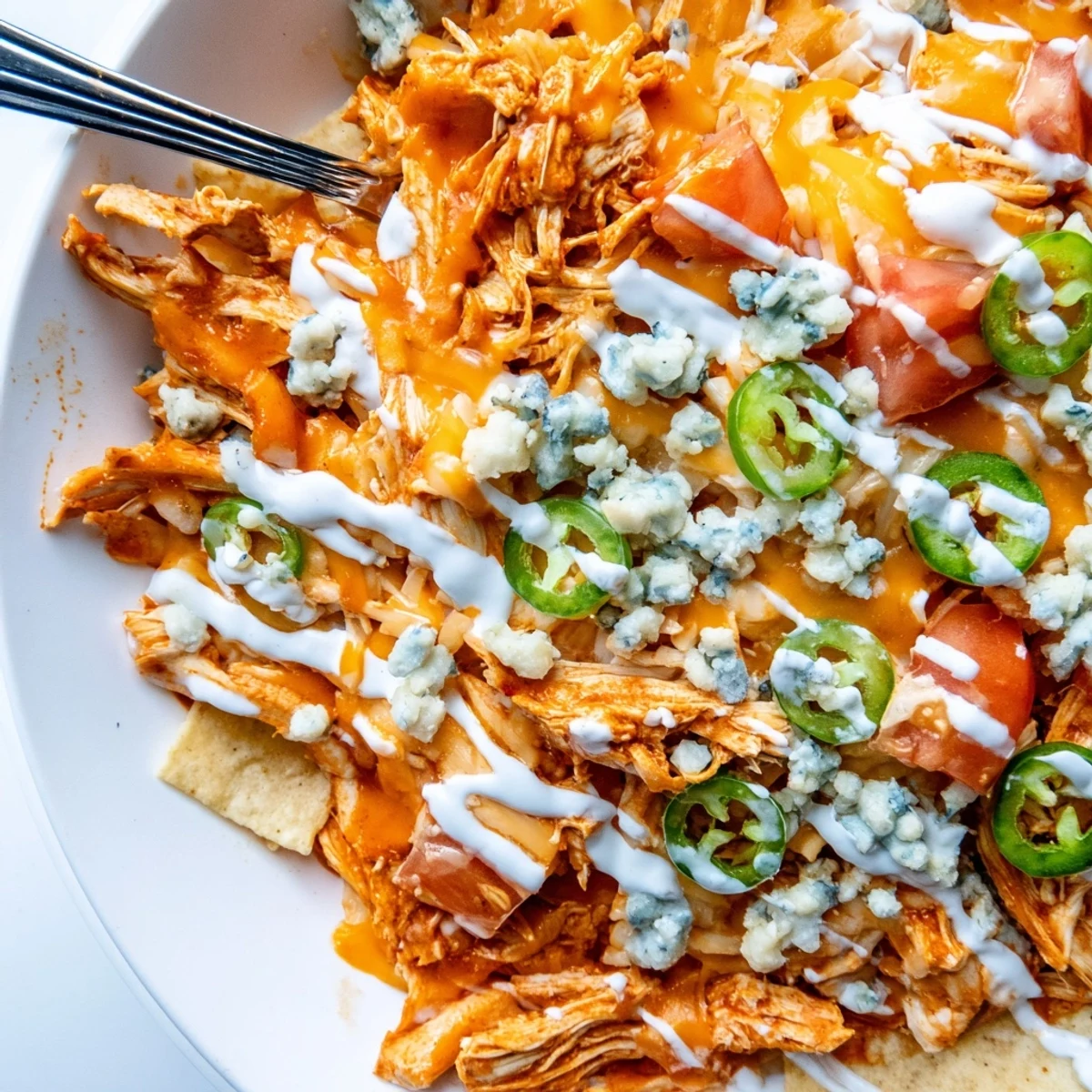 Crunchy tortilla base under Buffalo Chicken Nachos topped with shredded chicken, tomatoes, green onions