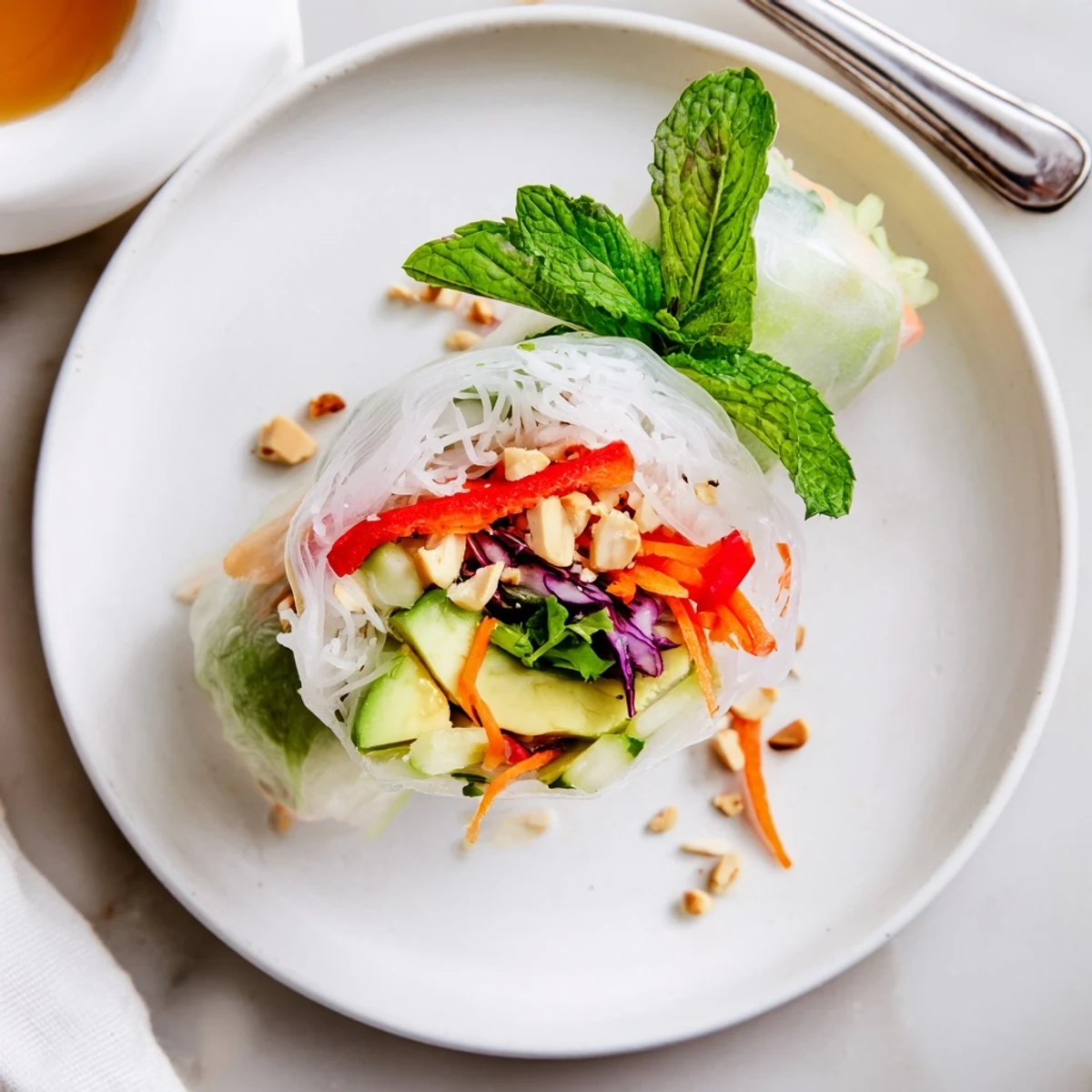 Hand-rolled Gluten Free Vegetable Spring Rolls resting on platter with crisp mint and cilantro
