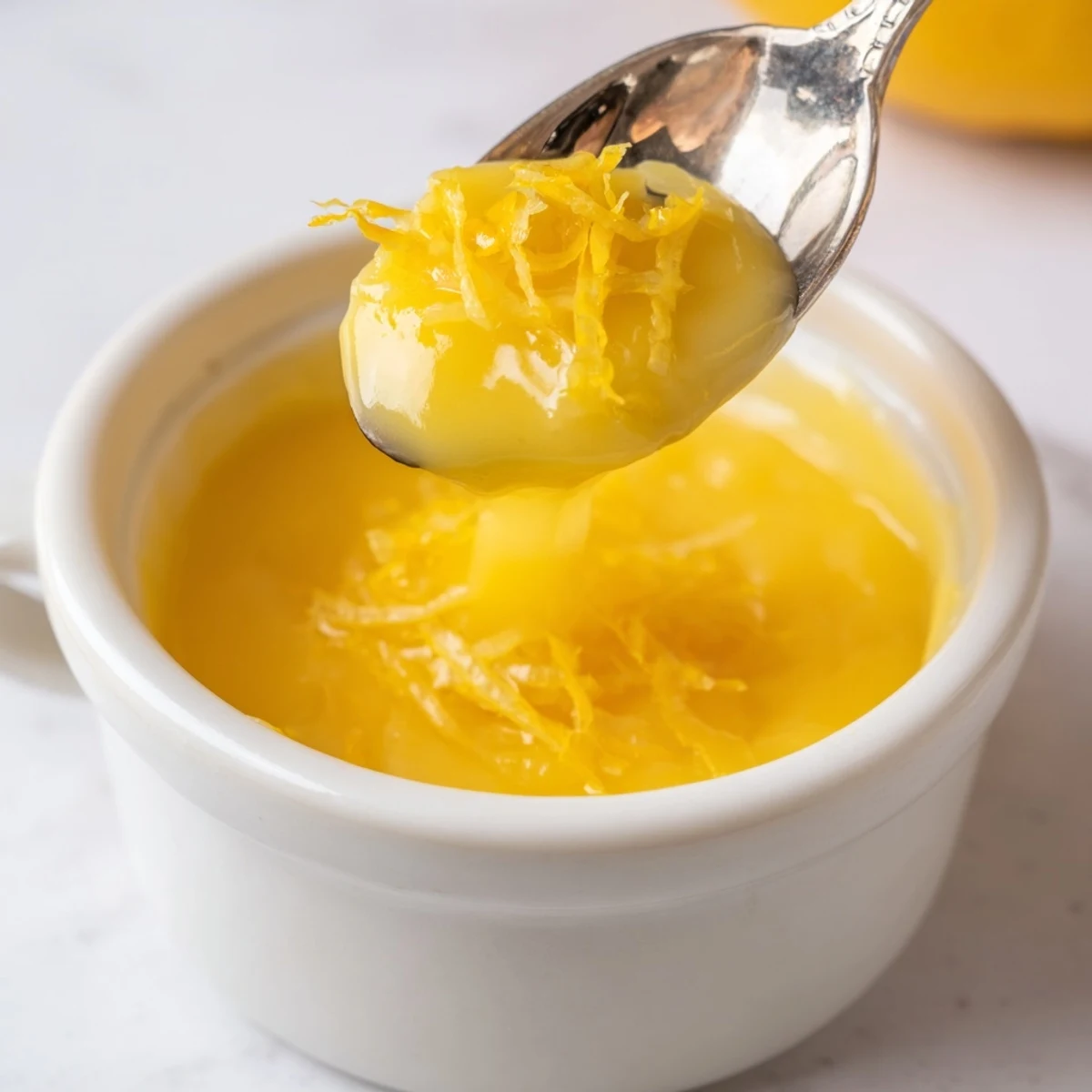 Homemade Lemon Curd gleaming golden, a silky texture spooned over warm scones
