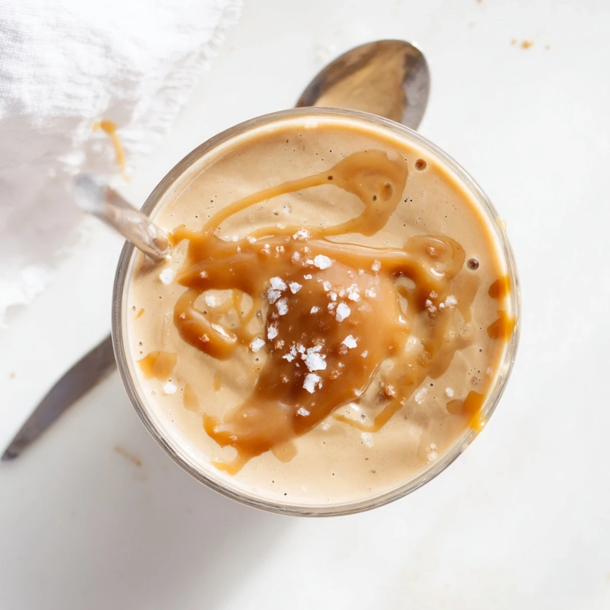 Creamy salted caramel protein smoothie topped with sea salt flakes and a banana slice
