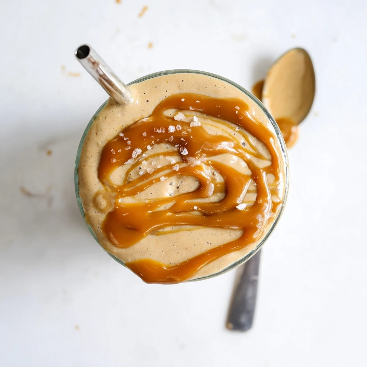 Golden salted caramel protein smoothie in a tall glass showing thick luscious texture