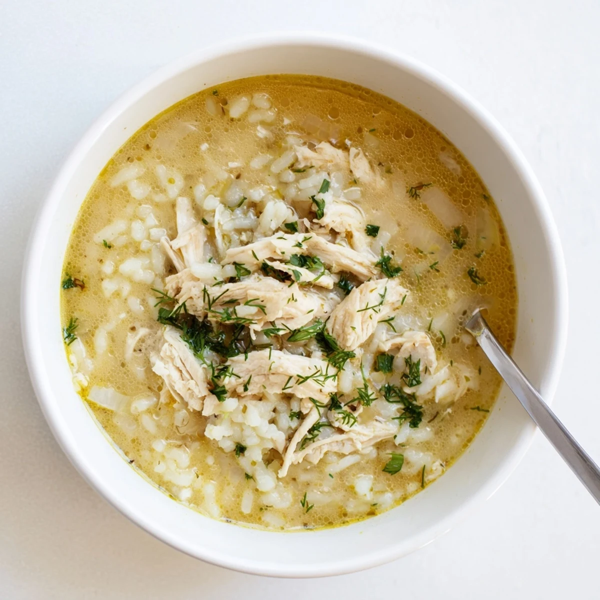 Steamy bowl of traditional Greek lemon chicken soup featuring fluffy rice and shredded chicken pieces