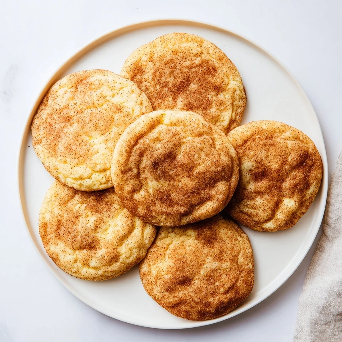 Golden Snickerdoodle recipe cookies with crackled tops dusted generously with spicy cinnamon sugar