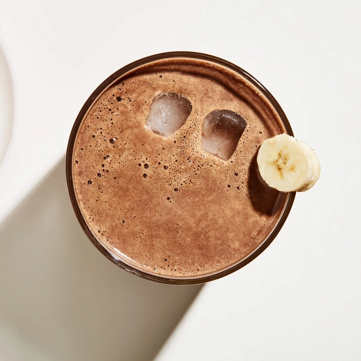 Thick chocolate peanut butter protein smoothie poured into a glass with melted drizzle on top