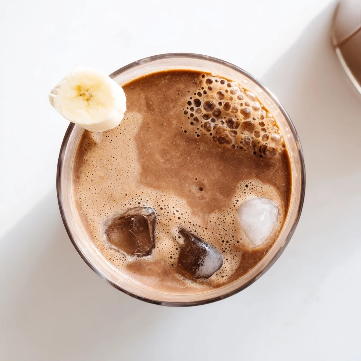 Rich chocolate peanut butter protein smoothie topped with banana slices and cacao nibs for breakfast