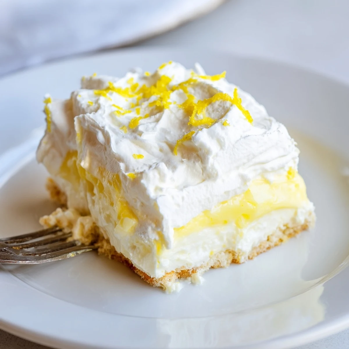 Creamy lemon lush cake dessert featuring zesty pudding layer on buttery golden crust