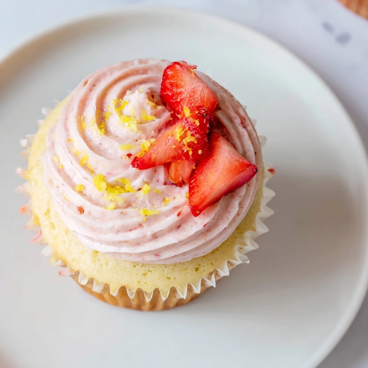 Light fluffy strawberry lemonade cupcakes with creamy strawberry frosting on white cake stand