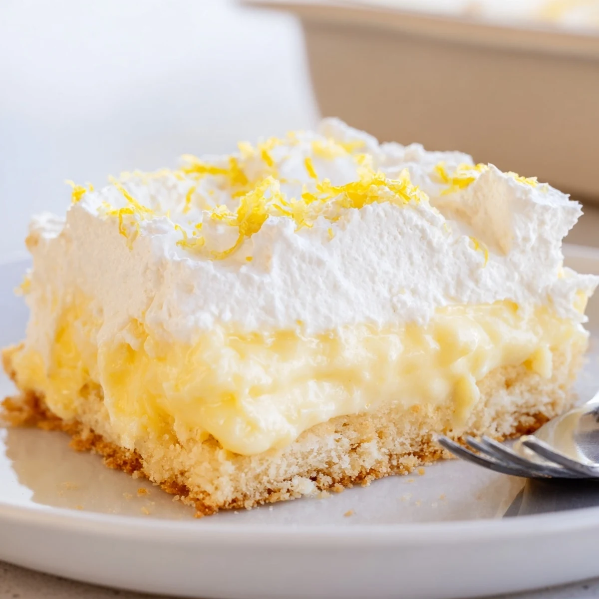 Sliced Lemon Lush Cake on glass dish, buttery crust and zesty filling