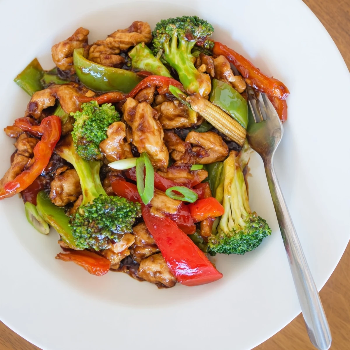 Spicy Hunan Chicken plated alongside tender carrot slices and baby corn for a vibrant dinner