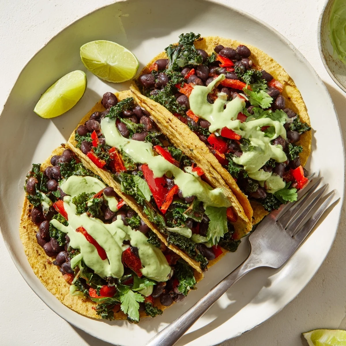 Golden corn tortillas loaded with smoky black bean kale tacos and creamy herb sauce