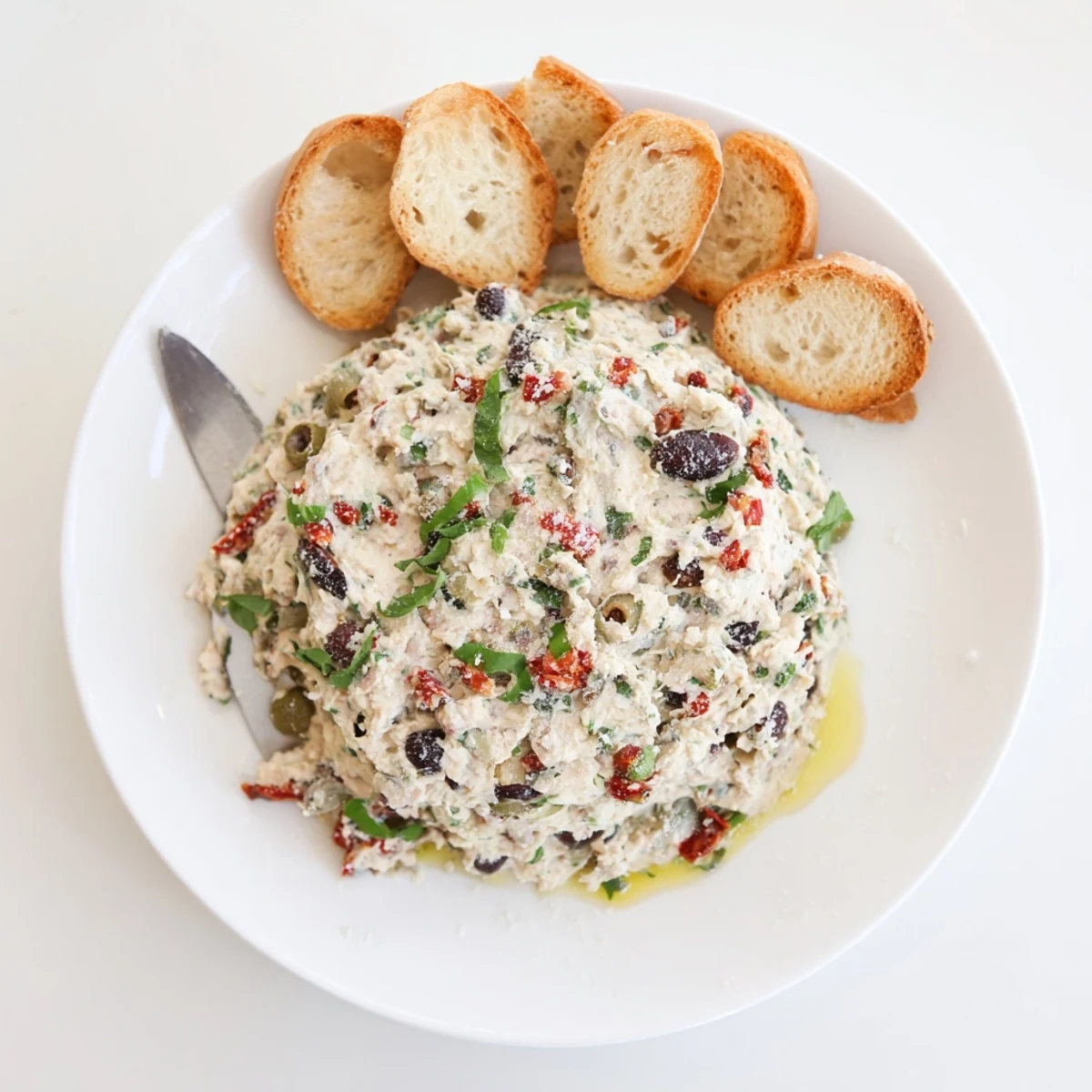 A rustic bowl of Italian Style Olive And Cheese Spread topped with chopped olives and herbs