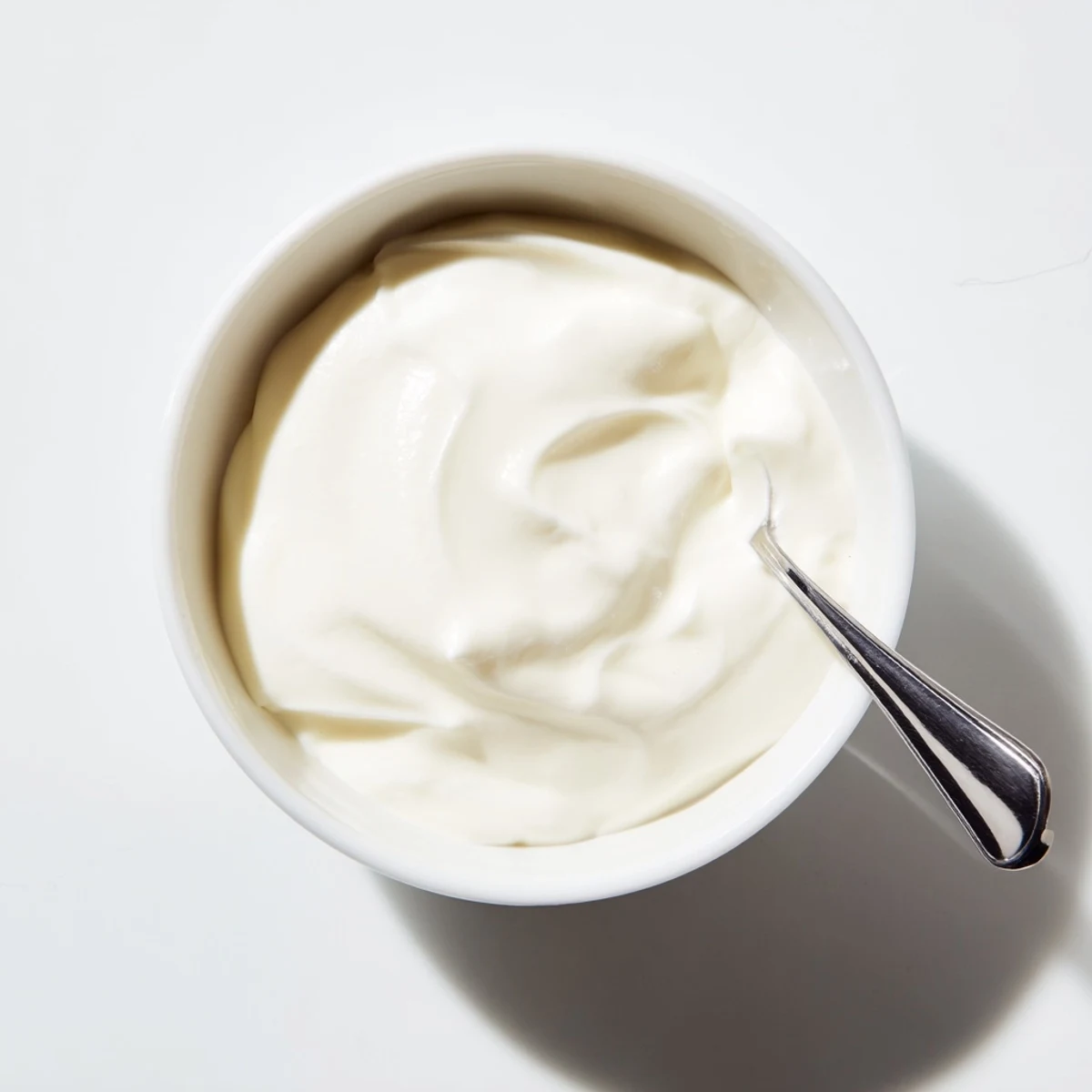 Thick tangy homemade yogurt swirled in a bowl with a drizzle of golden honey