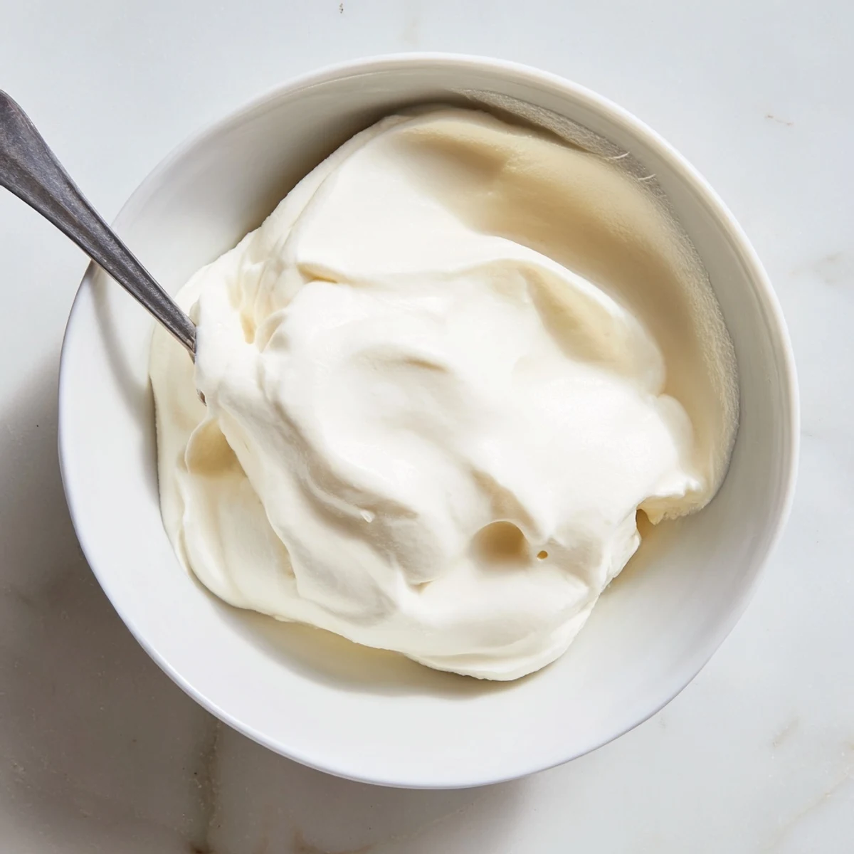 Smooth homemade yogurt garnished with crunchy granola and sliced ripe strawberries