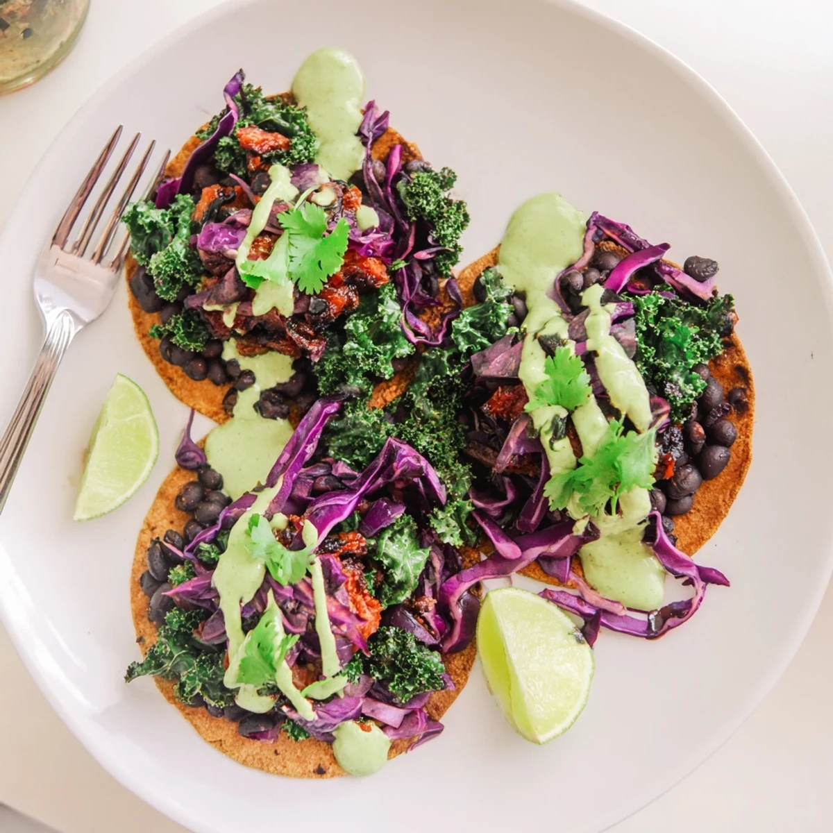 Smoky black bean kale tacos drizzled with vibrant green sauce on warm corn tortillas