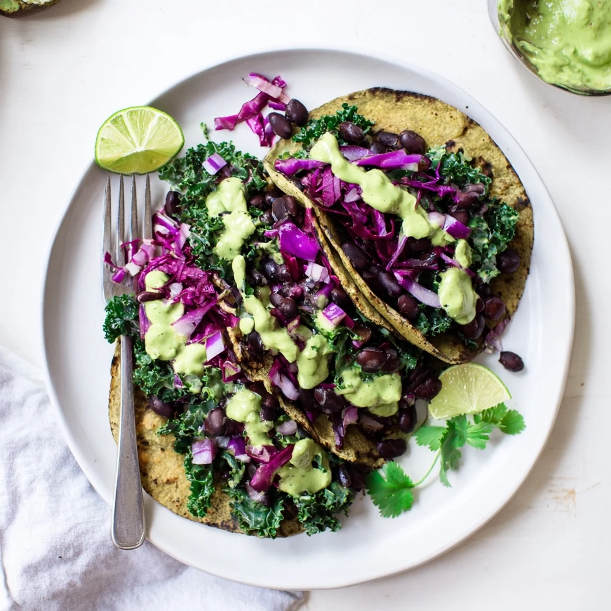 Warm corn tortillas loaded with smoky black beans sautéed kale and creamy green sauce