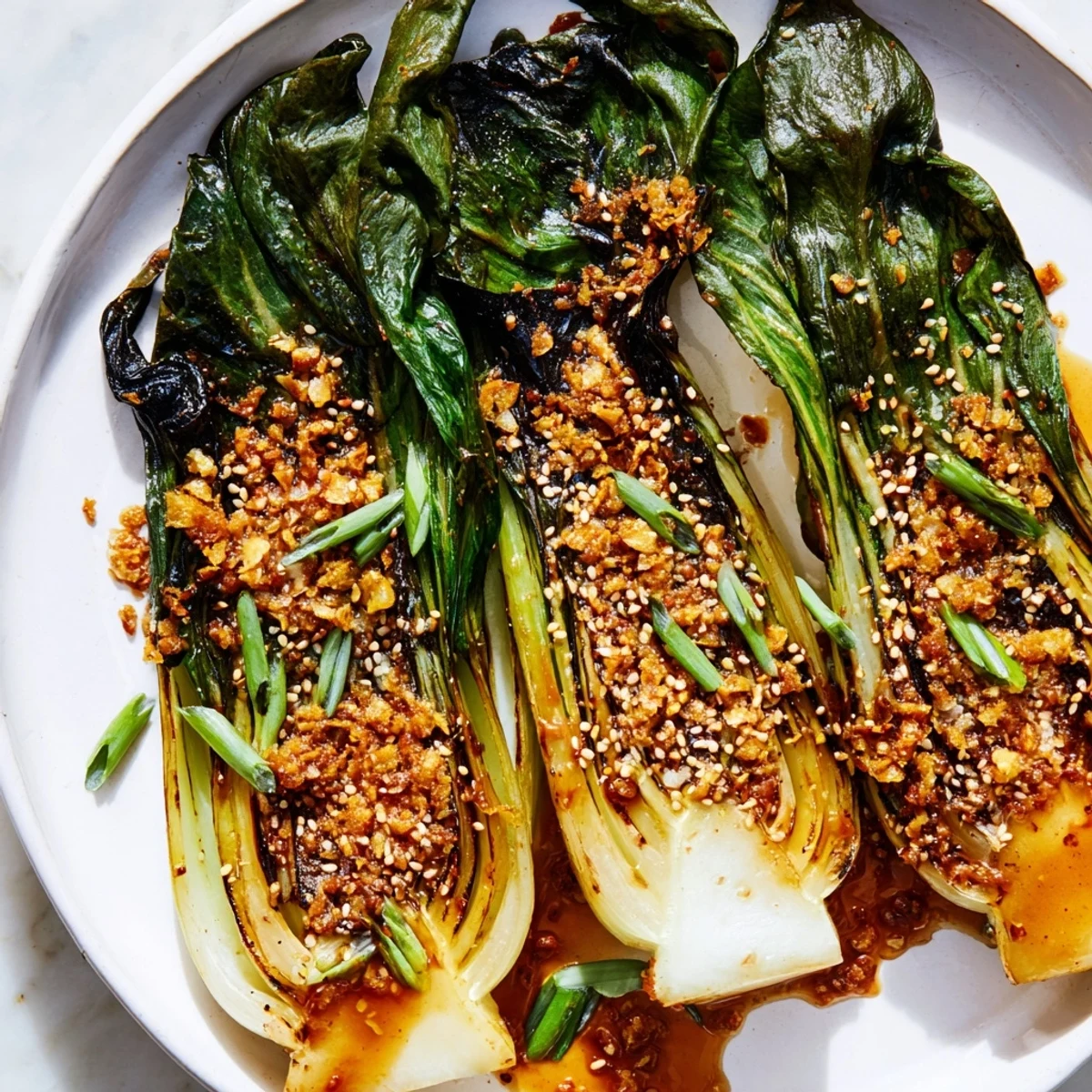 Tender caramelized garlic bok choy arranged on a platter topped with sesame seeds and green onions