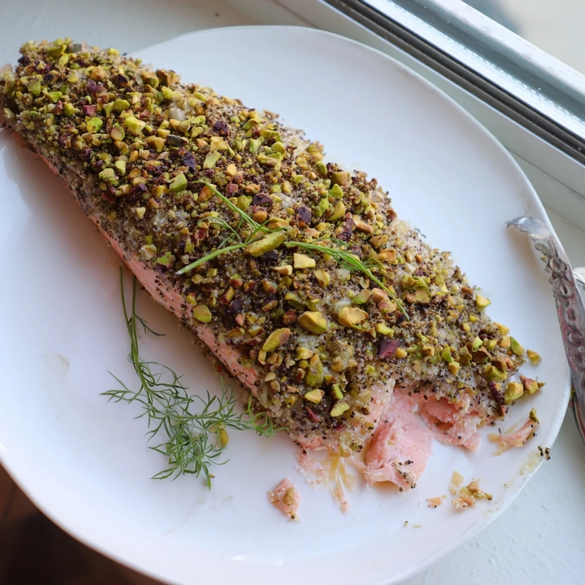 Oven-baked maple pistachio salmon topped with golden crushed nuts on a parchment-lined sheet
