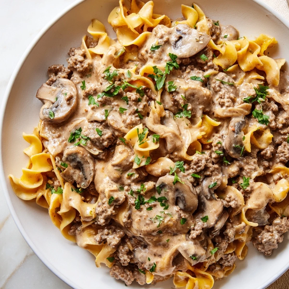 Creamy hamburger stroganoff served over tender egg noodles with fresh parsley garnish