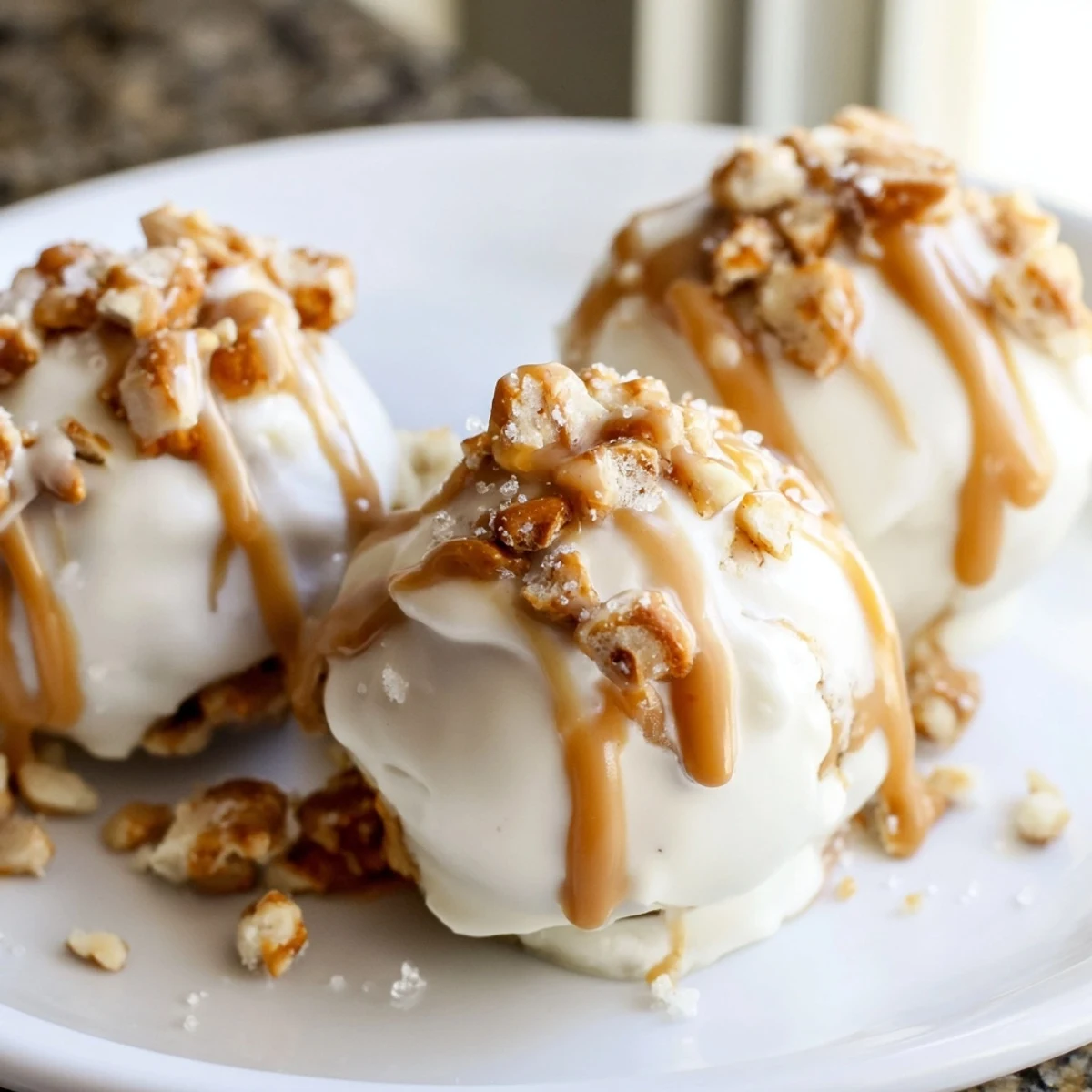 Creamy salted caramel pretzel cheesecake balls drizzled with golden caramel on a rustic tray